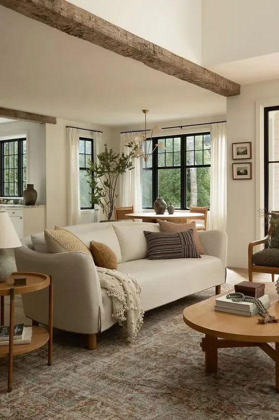 an earthy living room with a neutral sofa, a green chair, a low coffee table and a side table, a rough wooden beam