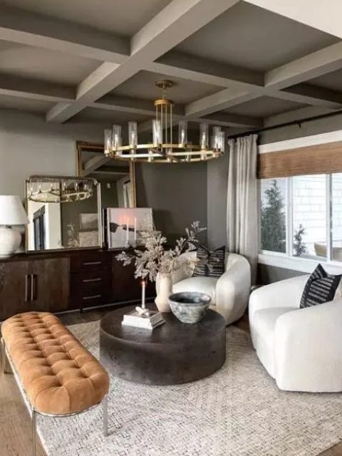an elegant living room in earth tones, with gray walls and ceiling, a dark stained sideboard, white chairs, a round coffee table and a rust-colored upholstered bench