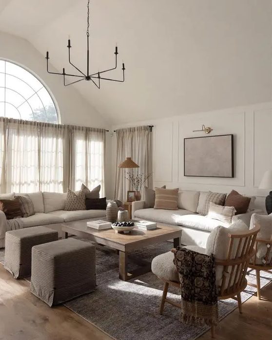 an earthy living room with cream sofas, a low coffee table, taupe stools, cream chairs and printed cushions
