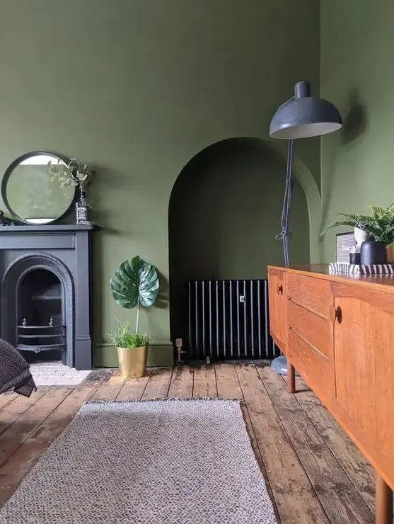 an olive green vintage living room with a non-working fireplace, a niche with a sideboard, a stained sideboard, a gray floor lamp and a mirror