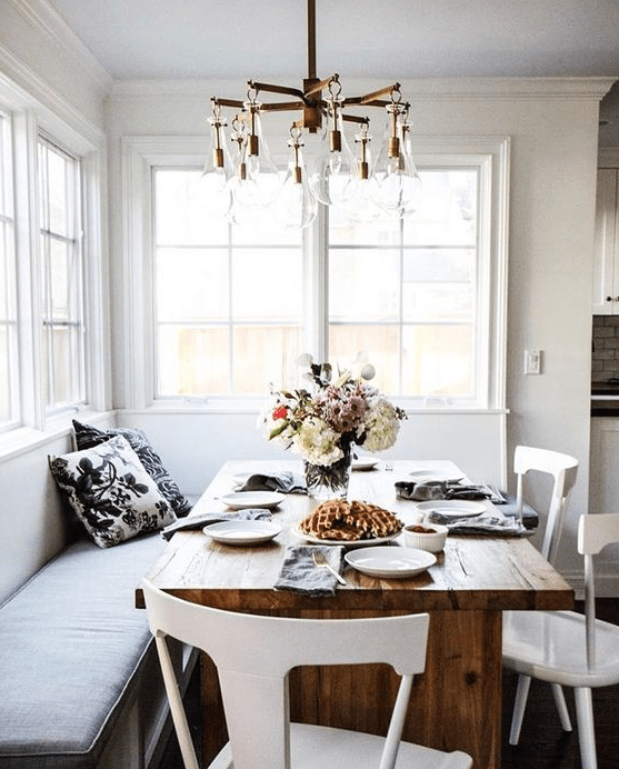 A chic breakfast nook or dining area with a corner sofa and wooden table is flooded with natural light
