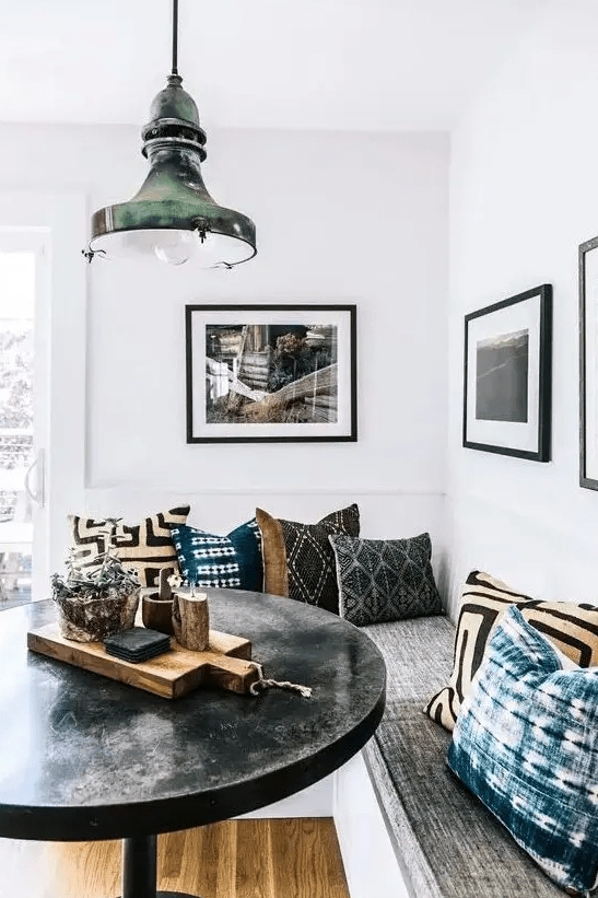 a corner banquette seating area with interior storage and a round concrete table and a vintage metal pendant lamp