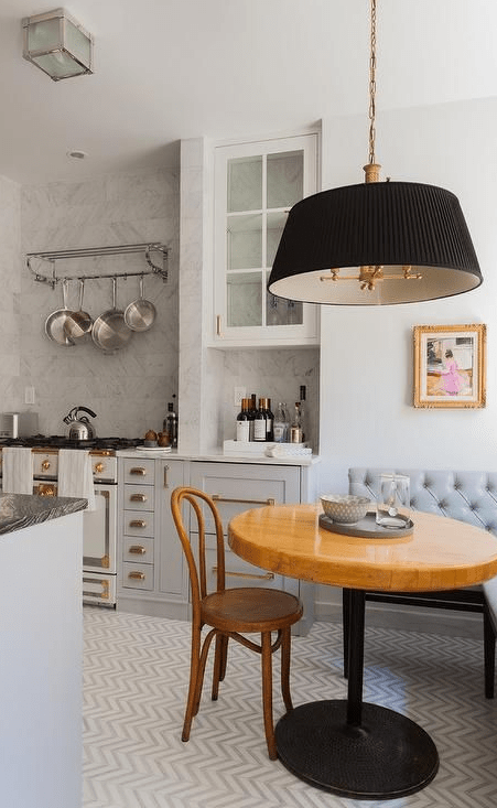 a French kitchen with gray and white cabinets, a corner dining area with a gray corner bench and a black pendant light