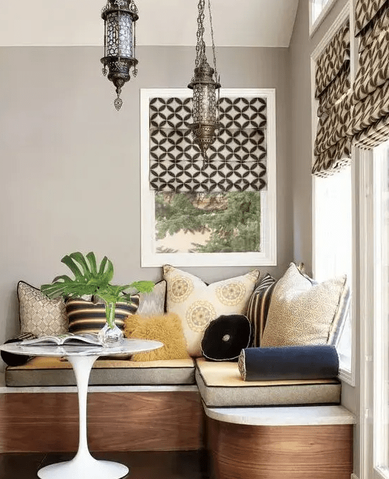 a luxurious banquette seating with lots of pillows and pillows as well as storage space inside as well as beautiful Moroccan pendant lamps