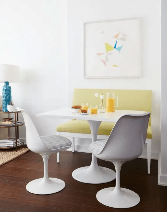a modern and bright breakfast nook with a mustard love seat, white table and striking white upholstered chairs