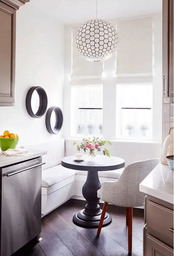a white corner banquette and a small black round table for a small breakfast nook by the window