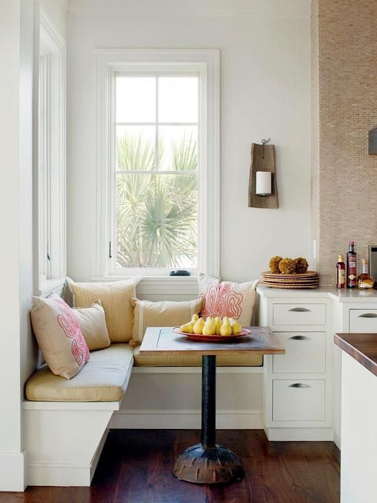 A super small breakfast nook with patterned pillows on a corner banquette and a small table can be squeezed into a kitchen