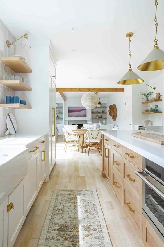 a light-filled farmhouse kitchen with white and stained cabinets, open shelving, pendant lamps and white stone countertops