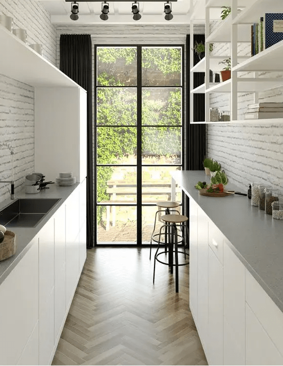 a modern white gallery kitchen with elegant cabinets, gray stone countertops, open shelving and brick walls