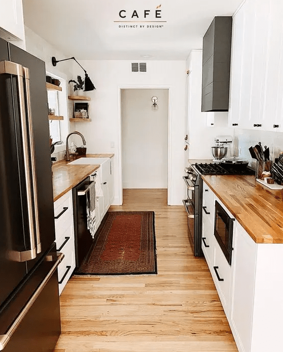 a small and cozy farmhouse kitchen with white cabinets, butcher block countertops, black handles, open shelving and a black sconce