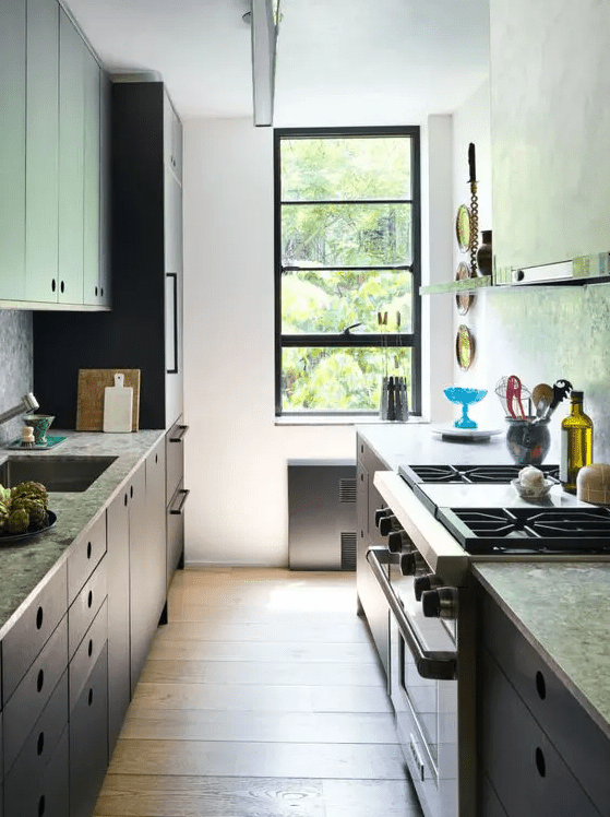 a small galley kitchen with gray stone countertops, open shelving, some appliances and a small black-framed window