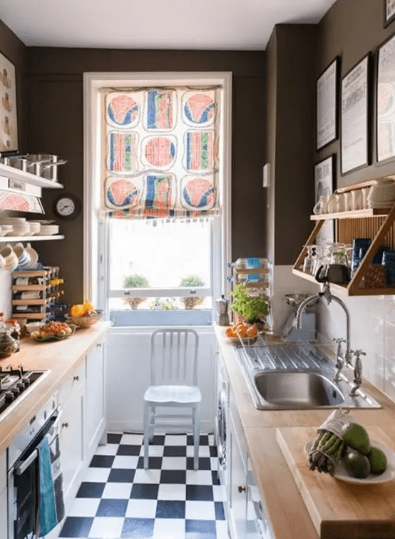 a small, monochromatic kitchen with black walls, a white subway tile backsplash, butcher block countertops and a colorful screen