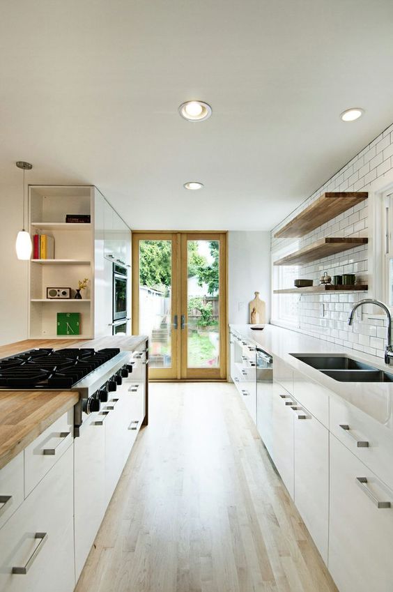 a modern, neutral galley kitchen with white cabinets and butcher block countertops, plus a white subway tile backsplash
