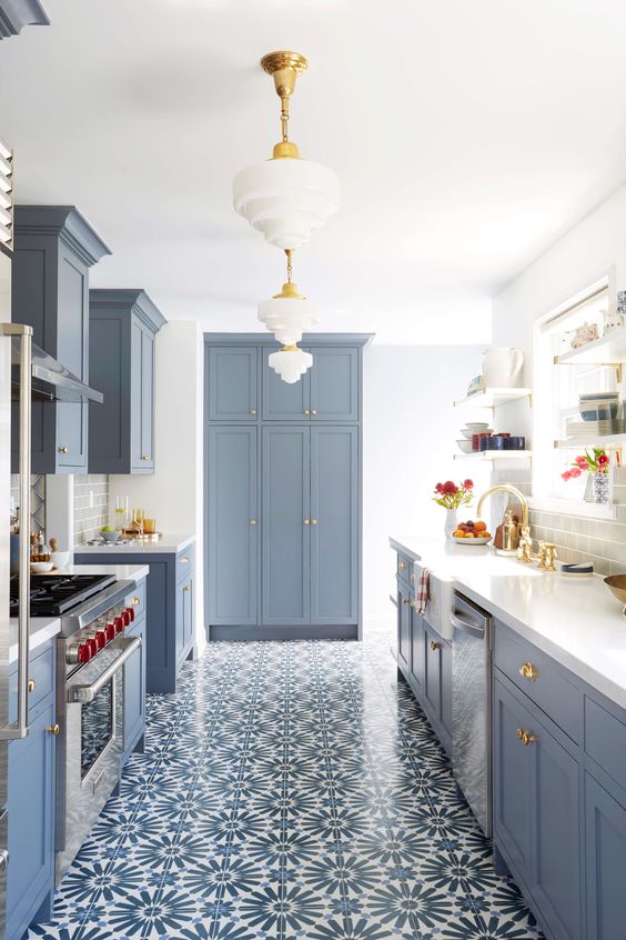 a modern farmhouse kitchen in powder blue with mosaic tile flooring, elegant pendant lamps and gilded accents for added elegance