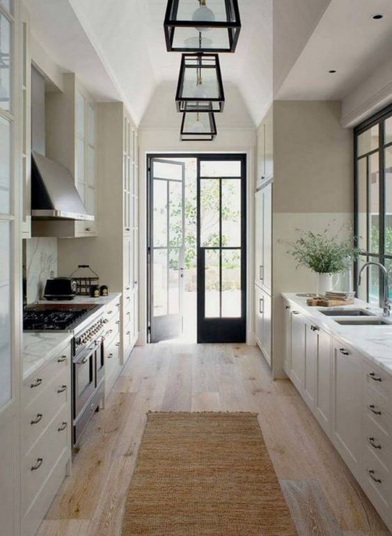 A vintage-style galley kitchen with white cabinets, white stone countertops and black accents for drama