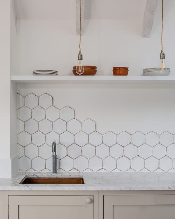 A beige kitchen with a white hexagonal tile backsplash, white marble countertops and open shelving looks good