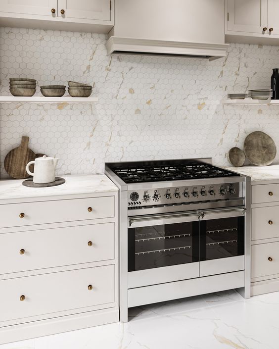 A modern, neutral kitchen with a beautiful hexagonal tile backsplash that imitates marble and white stone countertops