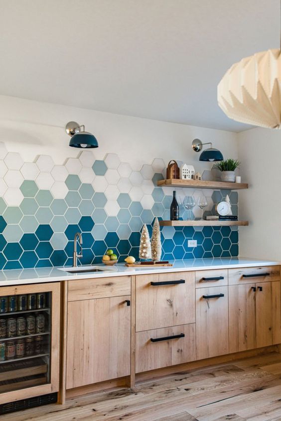 A modern stained kitchen with a striking ombre hexagonal tile backsplash and open shelving and black fixtures