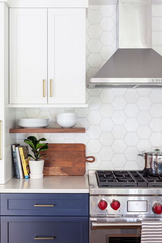 A navy and white kitchen with a white hexagon tile backsplash, open shelving, and stainless steel appliances is cool