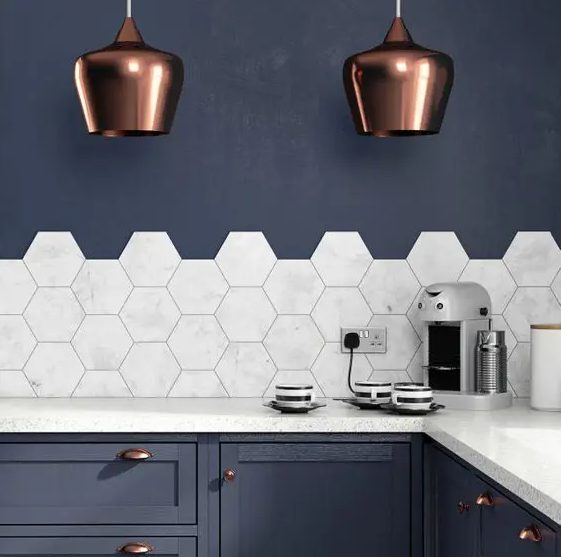 A navy blue kitchen with elegant copper accents and hexagonal marble tiles on the backsplash, creating a sophisticated feel