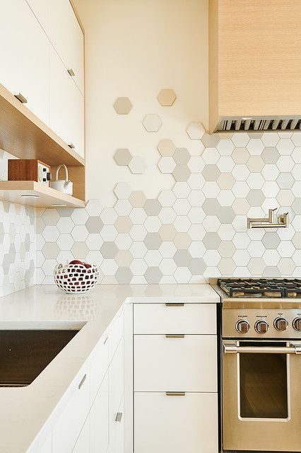 a neutral kitchen with a stained range hood, neutral stone countertops and a statement hexagonal tile backsplash