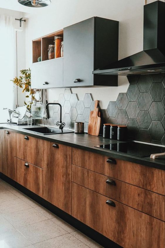 a richly stained kitchen with black countertops, black upper cabinets and a black hexagon tile backsplash
