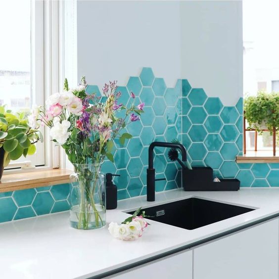 A sleek, minimalist white kitchen with a striking turquoise hexagonal tile backsplash and black fixtures is amazing