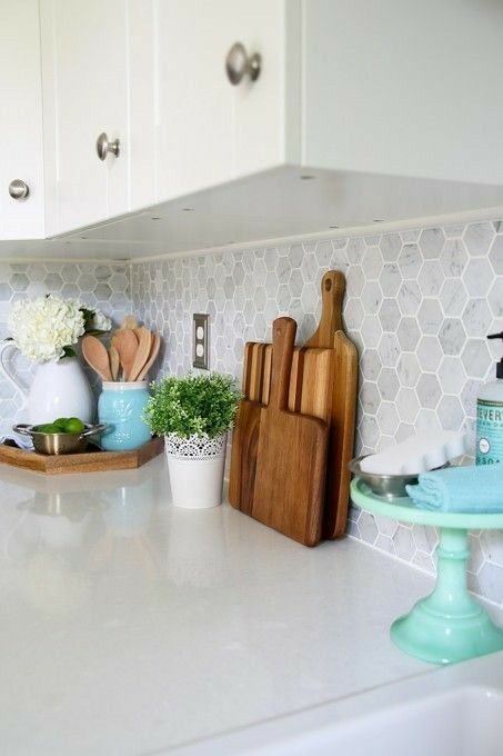 A white kitchen with a backsplash made of hexagonal white marble tiles and white stone countertops is a timeless idea