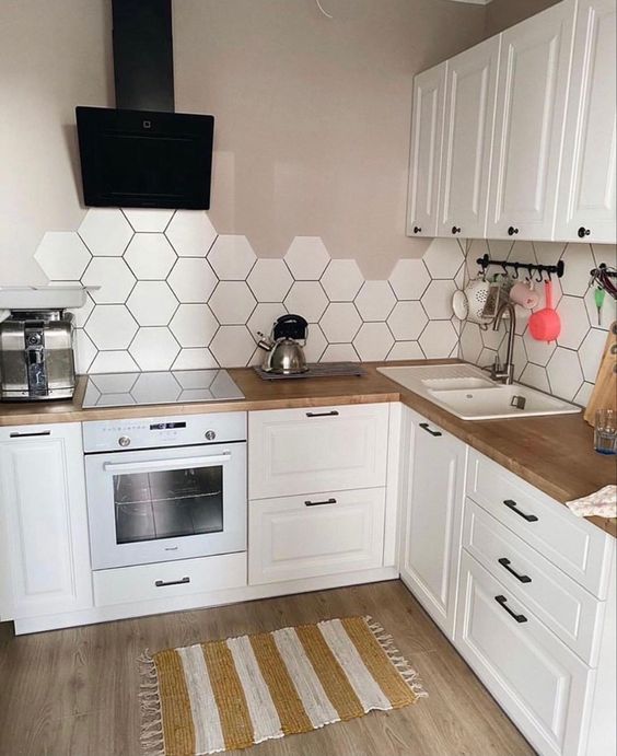 A white Scandinavina kitchen with greige walls, a white hexagonal tile backsplash and butcher block countertops is fantastic