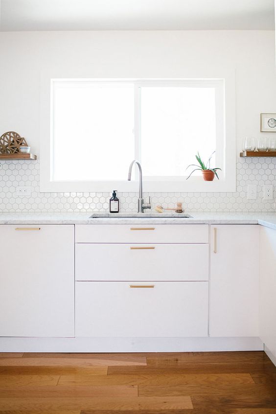 Small, hexagonal tiles on the backsplash add pattern and texture to the completely neutral kitchen