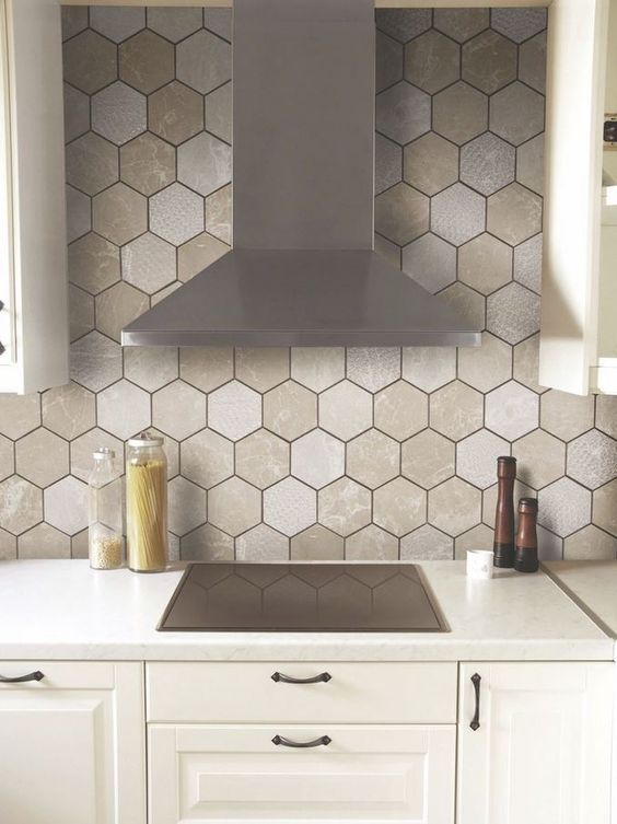 A backsplash made of hexagonal tiles in various neutral tones and with black grout adds interest to a neutral room