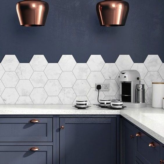 Medium marble hexagonal tiles accent the navy blue kitchen and create a contrasting look