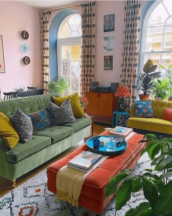 a bold, eclectic living room with pink walls, a green sofa, a neon yellow love seat, an orange ottoman, potted plants and bright artwork