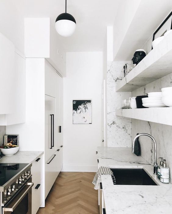 a small white Scandinavian kitchen with white marble countertops and backsplash and black accents